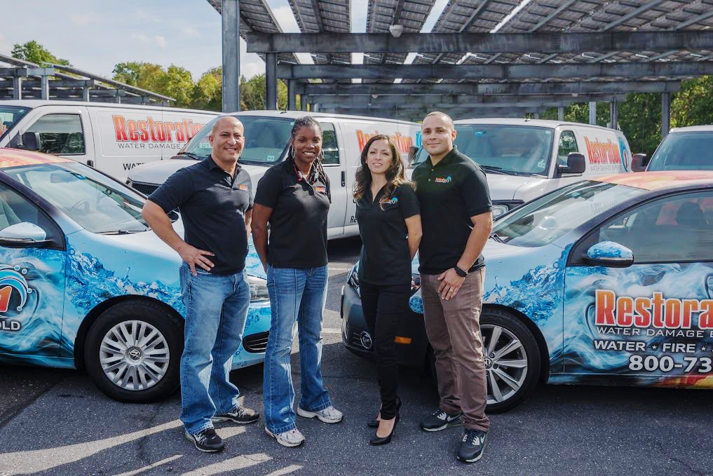 Restoration Franchise owners standing in front of their fleet of restorative vehicles